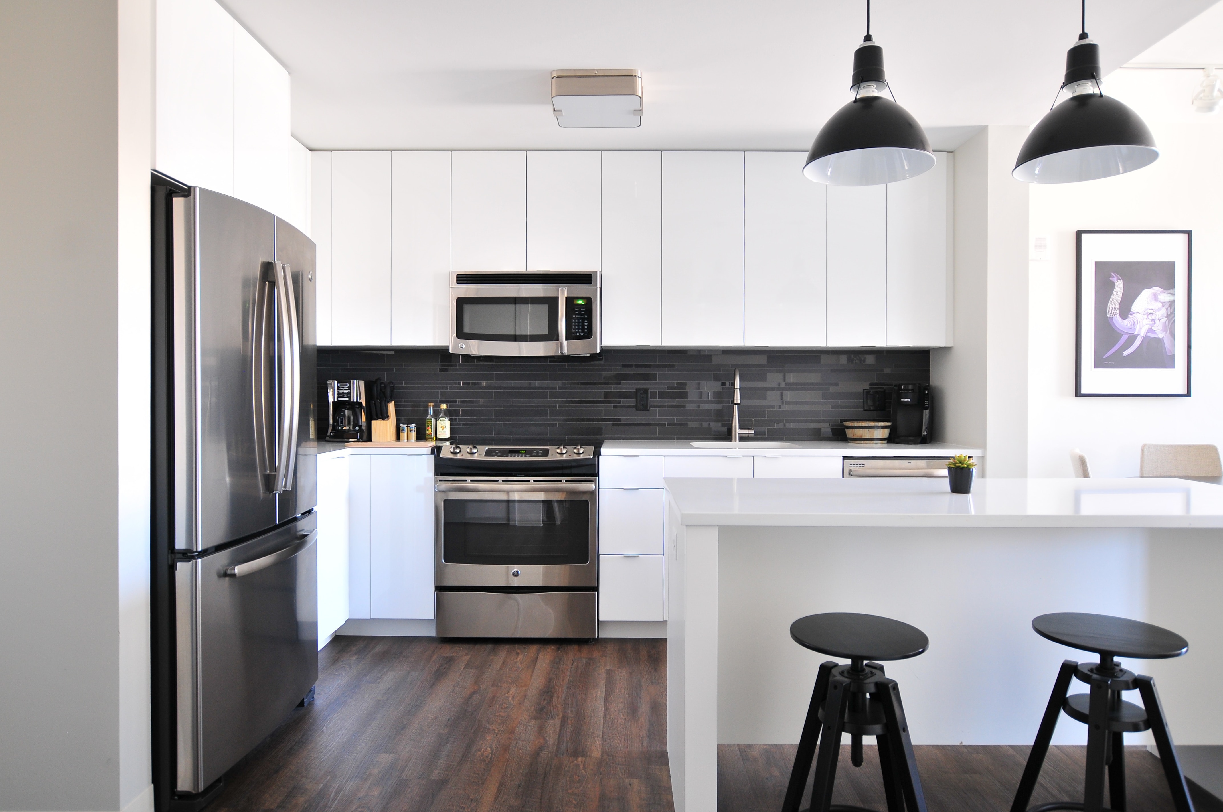 Clean kitchen with white cabinets and steel appliances