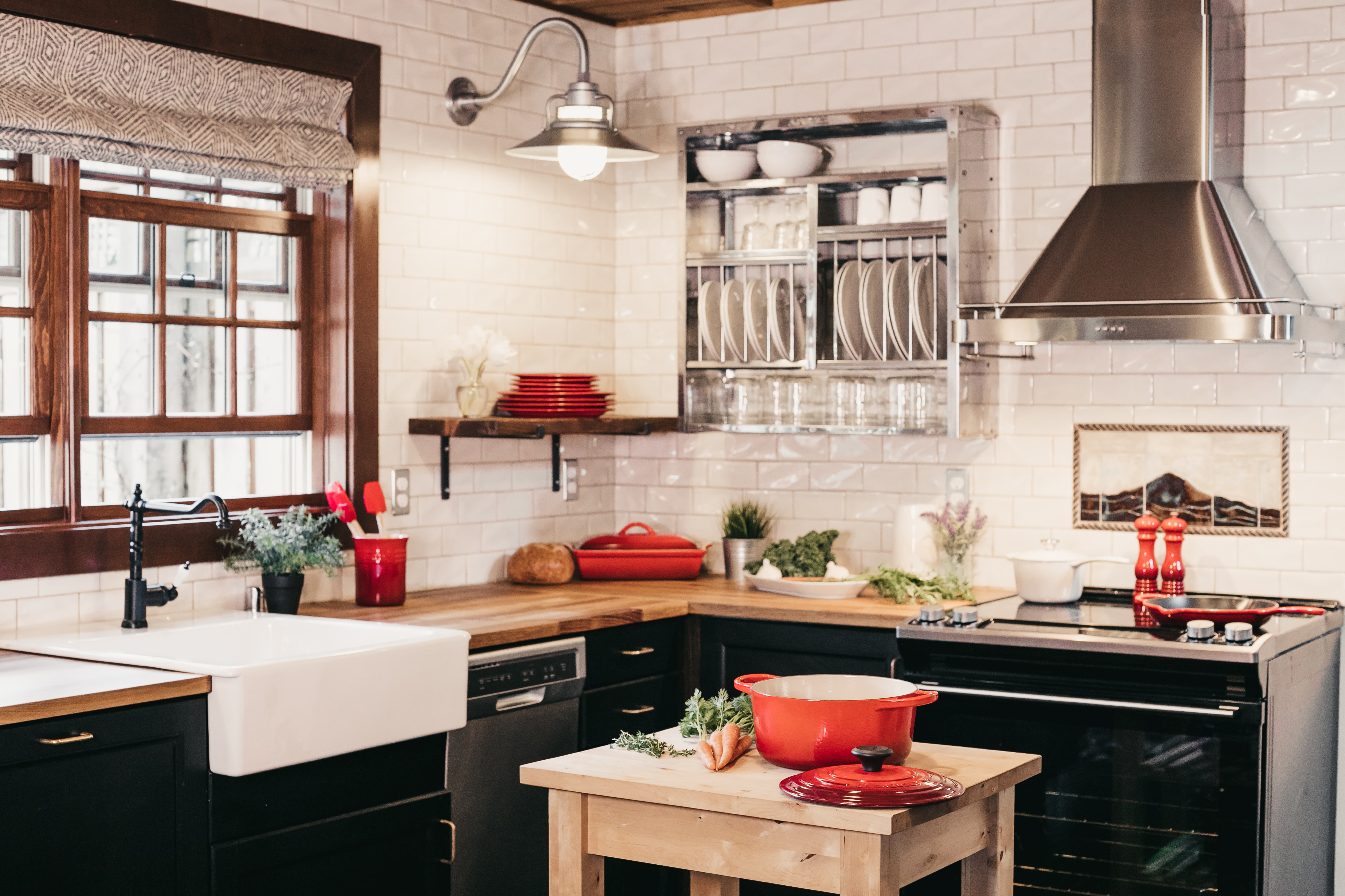 Large kitchen with black cabinets and red dishware